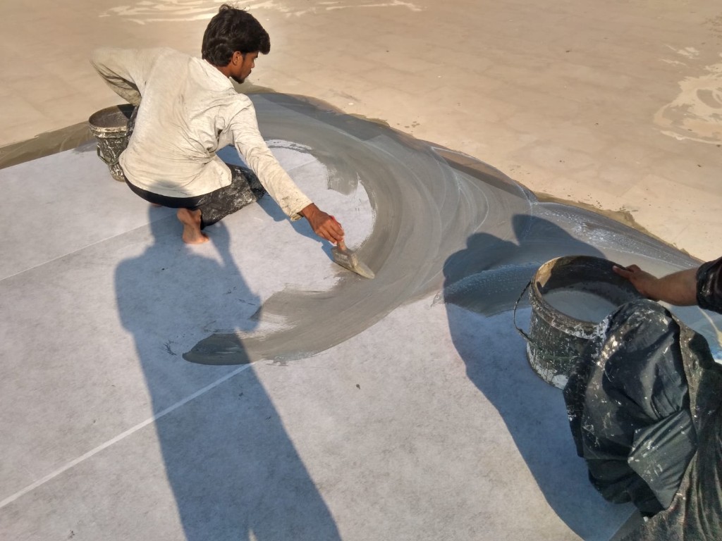 Waterproof chemical bucket on a grey coated rooftop with water tanks