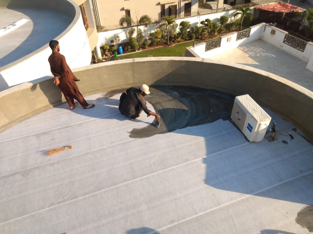 Technician applying liquid membrane over reinforcing fabric on a flat roof